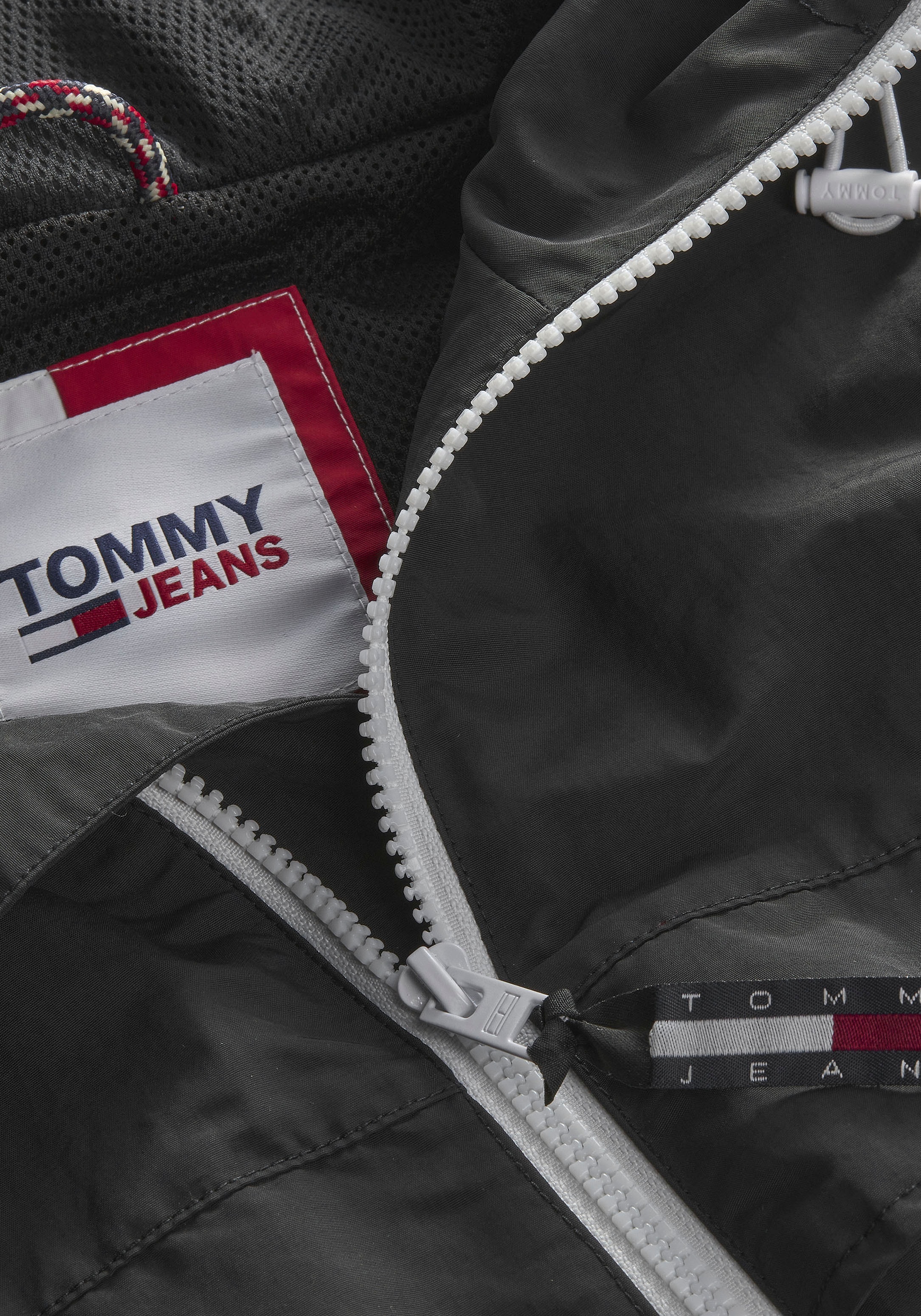WINDBREAKER«, online shoppen Tommy »TJM CHICAGO Windbreaker Jeans Zippern PLUS kleiner bei Kapuze, OTTO mit Logo-Prägung an mit Plus den