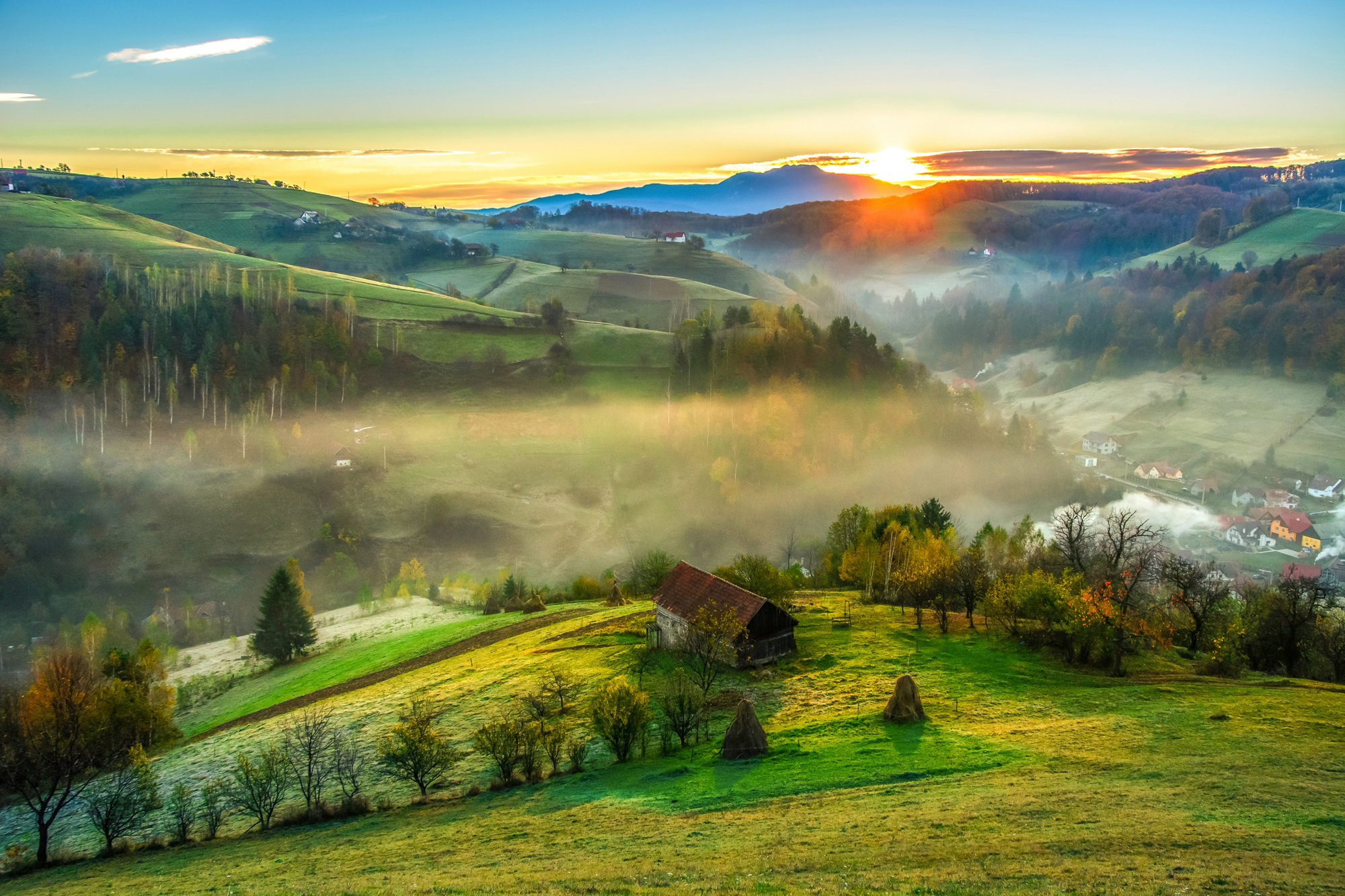 Fototapete »PANORAMA-LANDSCHAFT DORF WIESE NEBEL GEBIRGE SONNE WALD«