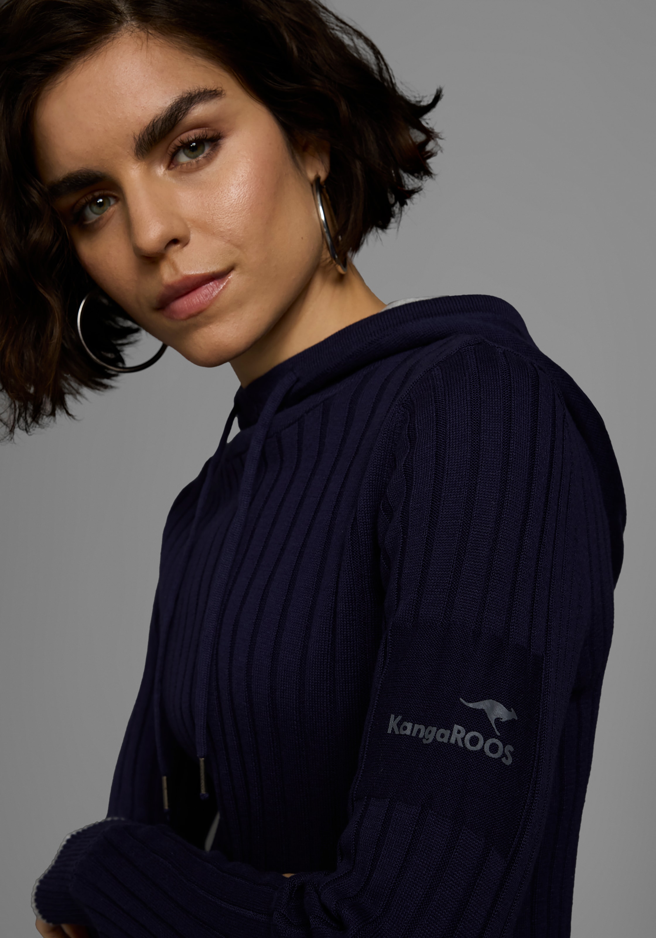 KangaROOS Strickpullover, mit kontrastfarbener Kapuzeninnenseite und Logodruck auf dem Arm